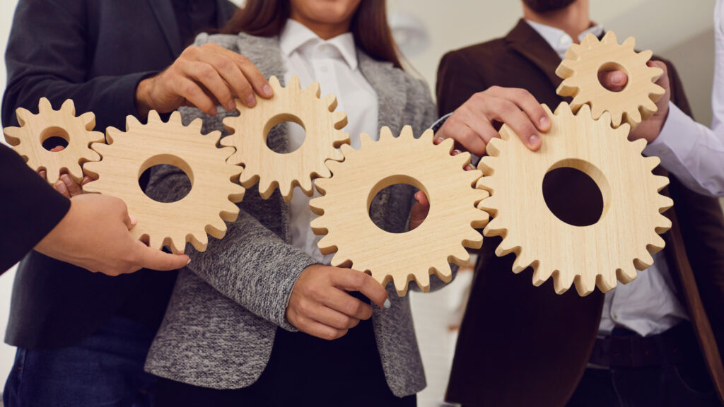 A team of business professionals holding enmeshed wooden gears