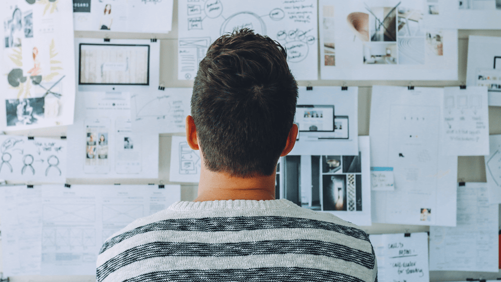 man looking at wall of sketches